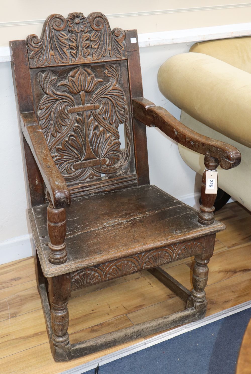 A 17th century carved oak panel-back open armchair, W.62cm